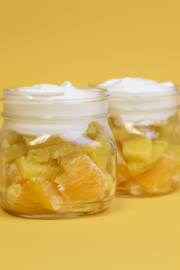 parfait2 Oranges, pineapple, and whipped topping in a clear mason jar to look like a candy cane on a yellow backdrop.