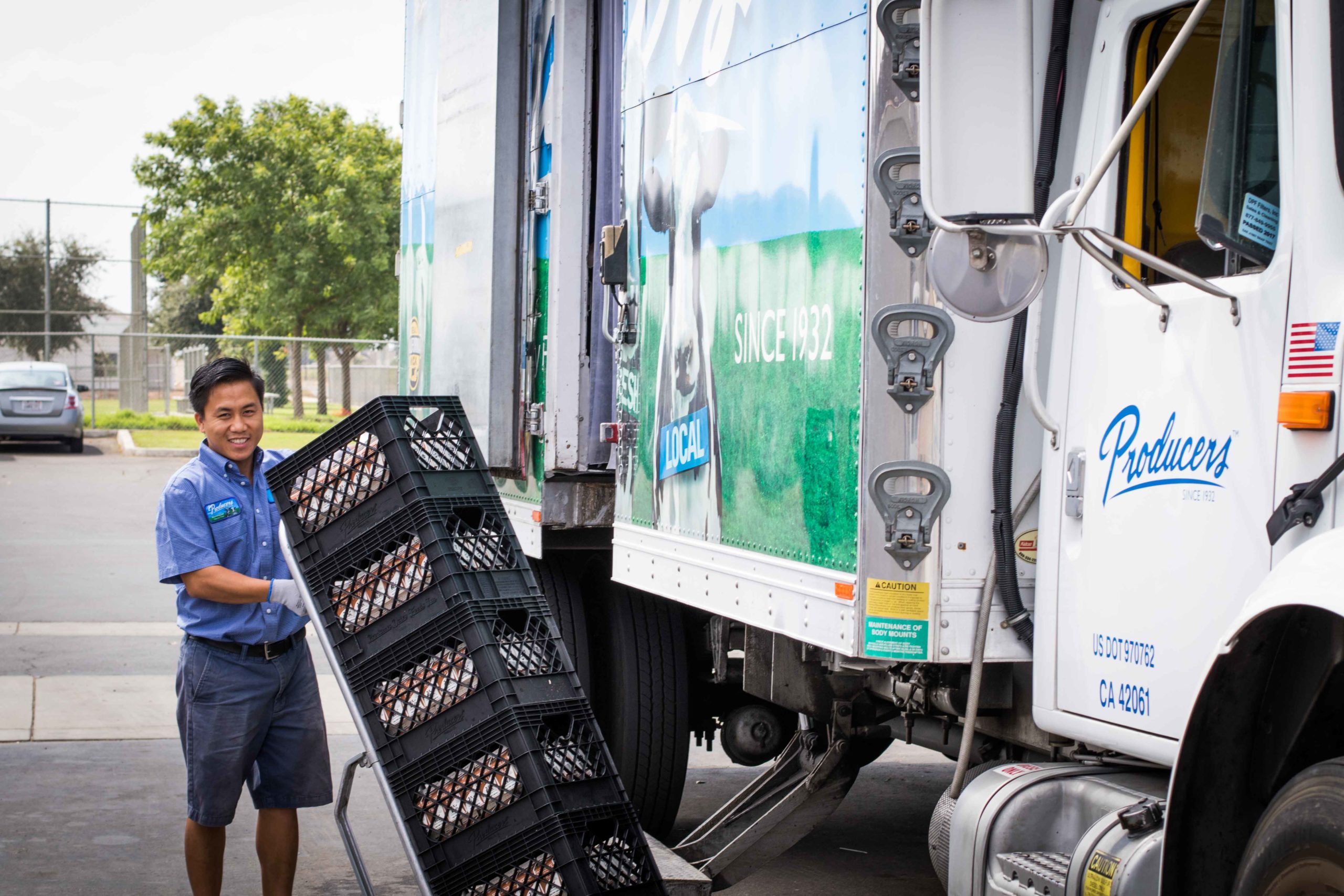 Smiling producers truck driver delivering milk to elementary school.